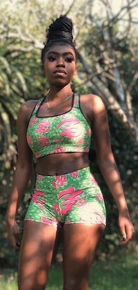 a Black model wearing a matching green and pink sports bra and yoga shorts