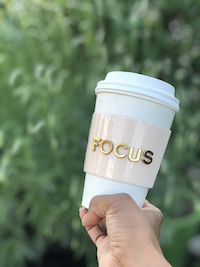 a coffee thermos with a pink sleeve that says the word focus in gold letters
